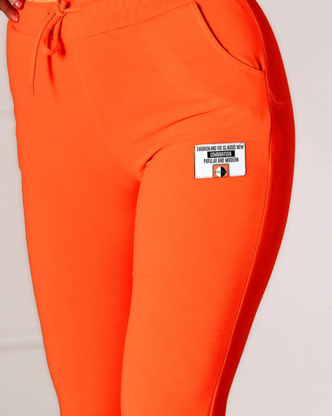Неоново-помаранчеві жіночі спортивні штани з нашивкою - Одяг